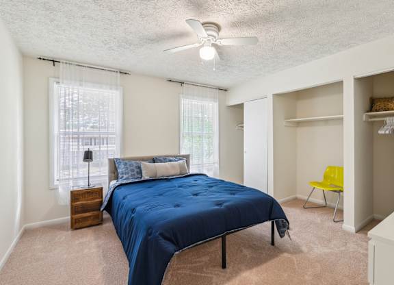A bedroom with a blue bedspread and a yellow chair.