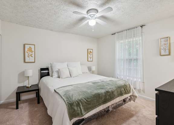 A bedroom with a bed, nightstand, and two pictures on the wall.