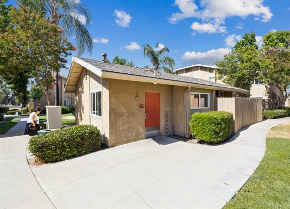 a small tan house with a red door and a sidewalk
