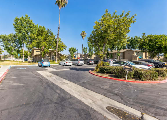 a parking lot with cars parked in front of some trees