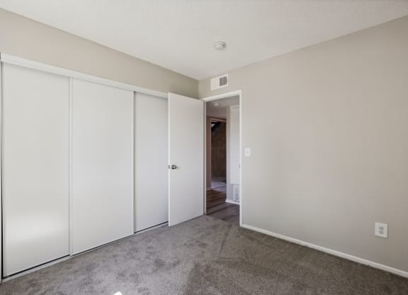 an empty bedroom with white closets and a carpeted floor