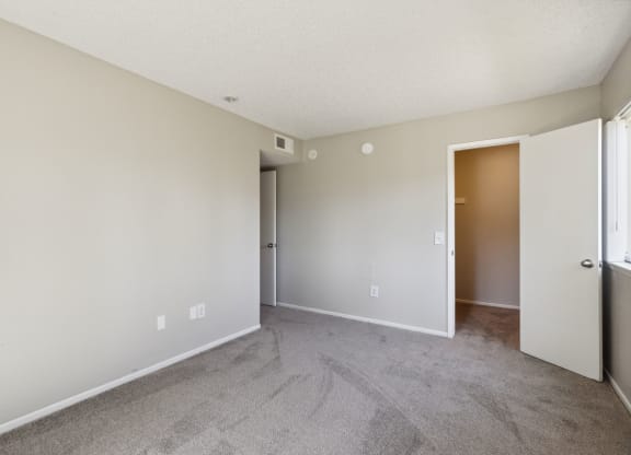 an empty living room with carpet and a door to a bedroom