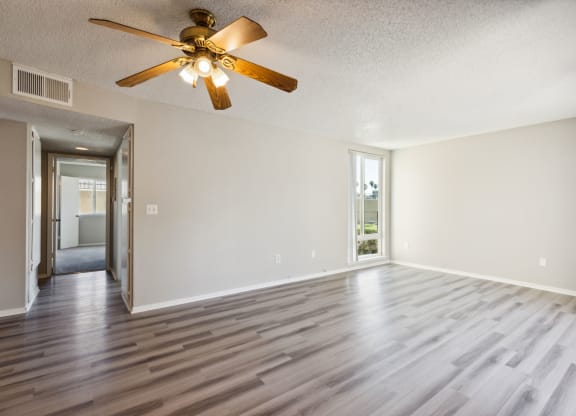 an empty living room with wooden floors and a ceiling fan