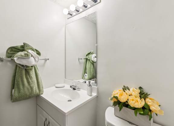 A white bathroom with a green towel hanging on the wall.
