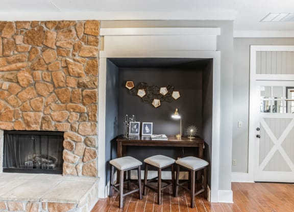 a living room with a stone fireplace and a bar with three stools