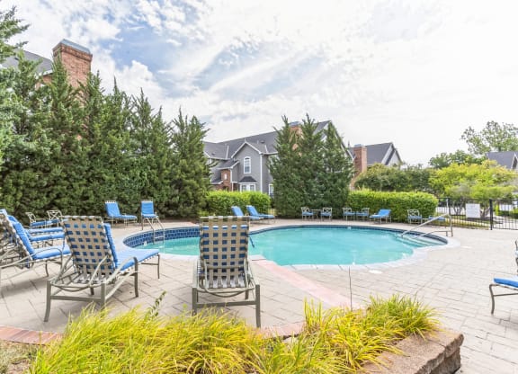 a swimming pool with blue chairs and chairs around it