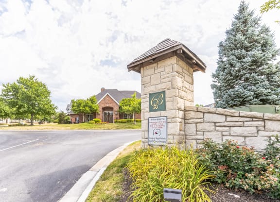 the front entrance of a house with a stone wall and a sign on the side