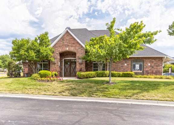 the front of a brick house with trees and grass