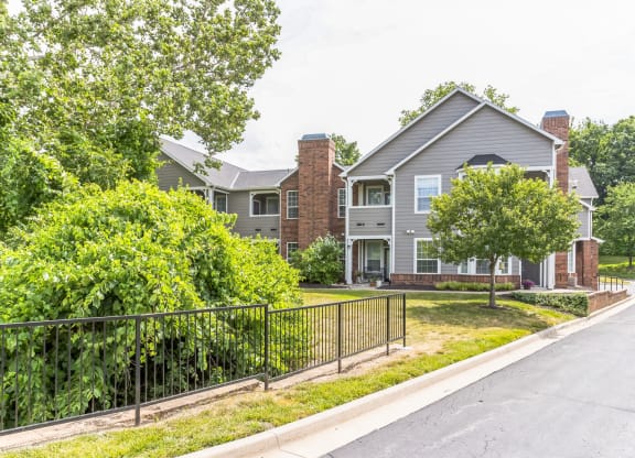 an empty street in front of a house with a fence