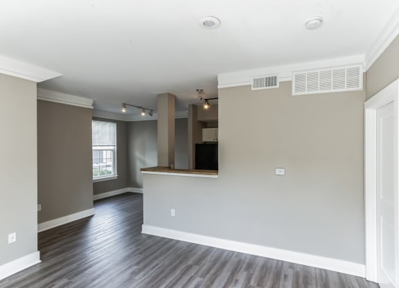 an empty living room and kitchen with wood flooring and a window