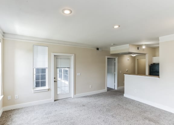 an empty living room with white walls and doors and a carpet floor