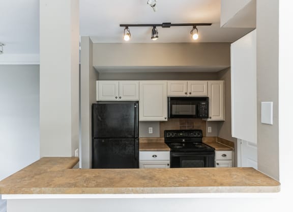 an empty kitchen with a counter top and a black refrigerator