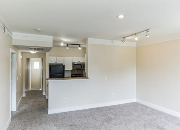 a renovated living room and kitchen with white walls and a carpet floor