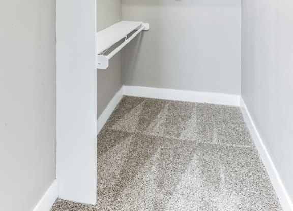 an empty closet with white shelves and a tiled floor
