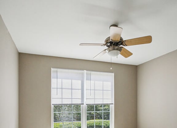 an empty room with a ceiling fan and a window