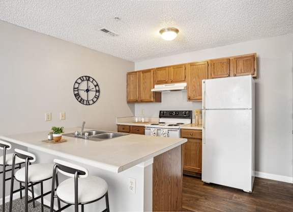 A kitchen with a white fridge and wooden cabinets.