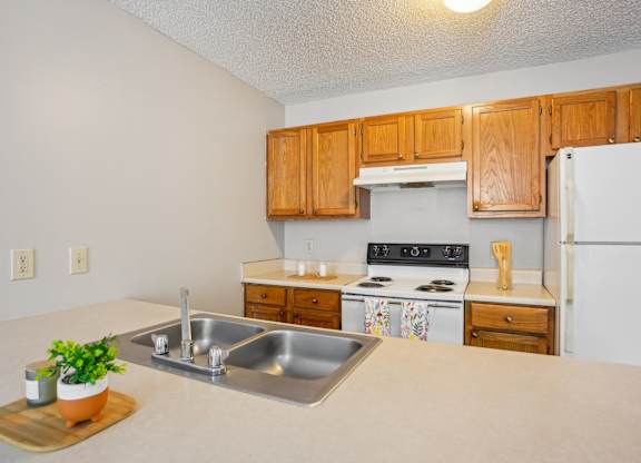 A kitchen with a stove, sink, and refrigerator.