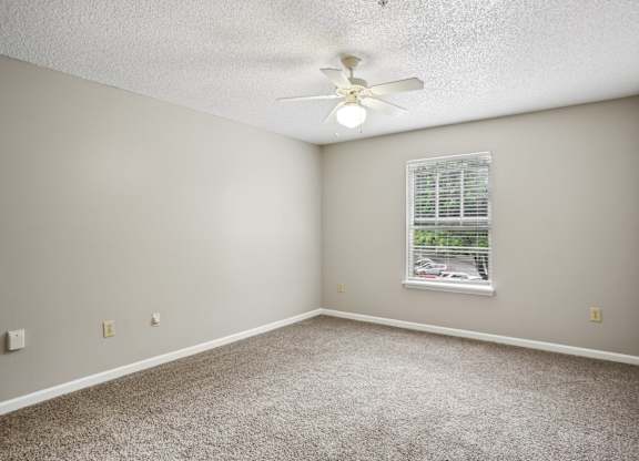 A room with a ceiling fan and a window with blinds.