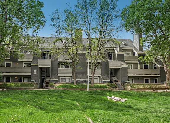 A large grey house with a green lawn in front.
