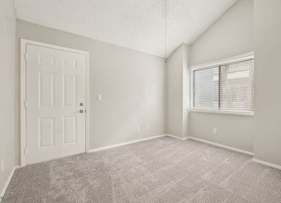 A room with a door and a window with blinds.