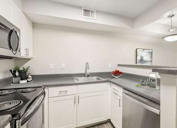 A kitchen with white cabinets and a stainless steel sink.