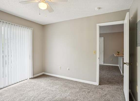 A room with a ceiling fan and carpeted floor.