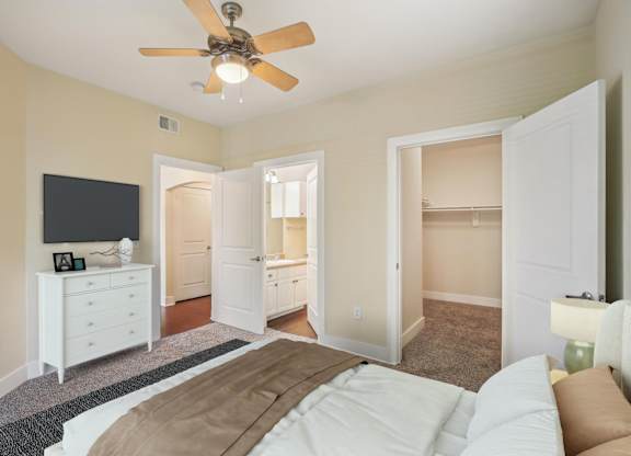 A bedroom with a bed, dresser, and television.