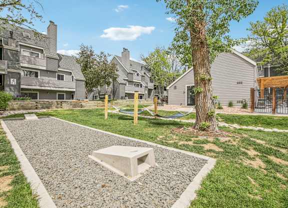 A gravel area with a white square in the middle and a tree to the right.