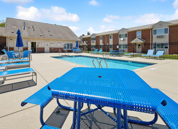 our apartments have a large pool with blue tables and chairs