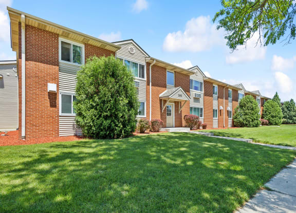 a row of brick apartment buildings with green grass and trees