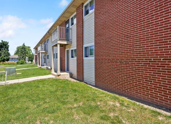 a brick apartment building with a lawn and a sidewalk
