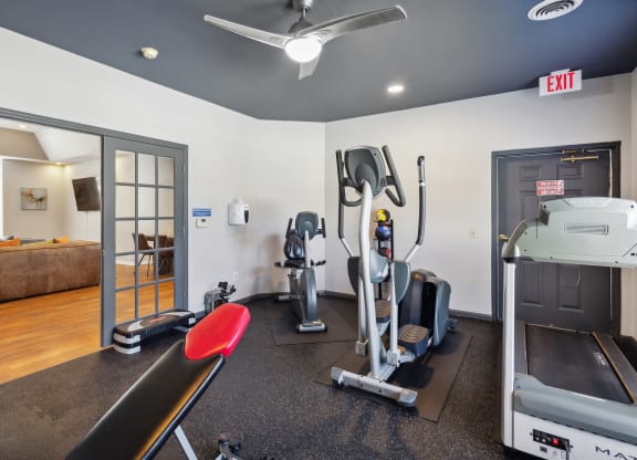 a gym with exercise equipment and a bed in the corner of a room