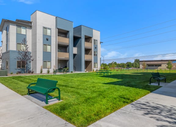 A modern apartment complex with a green bench in the foreground.