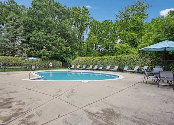 A small pool surrounded by trees and chairs.