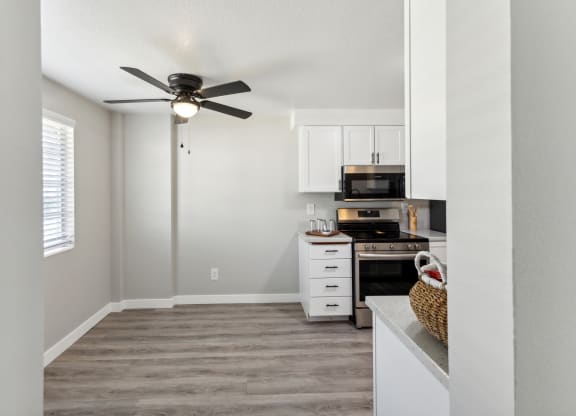 a kitchen with white cabinets and a ceiling fan