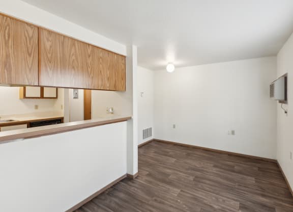 an empty living room and kitchen with wood flooring and a window