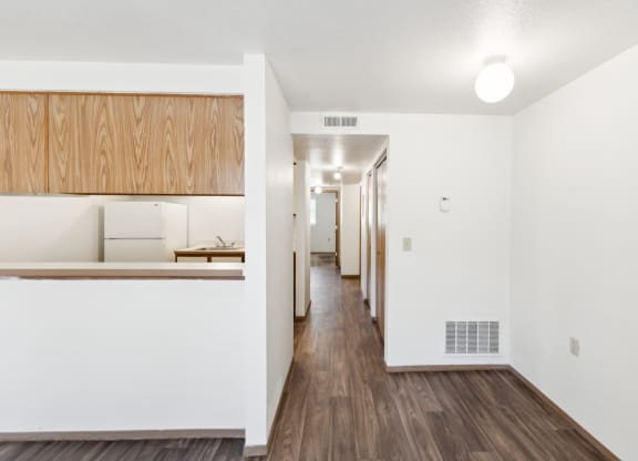 a renovated living room and kitchen with white walls and wood floors