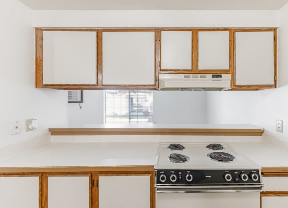 a kitchen with white cabinets and a stove and a window