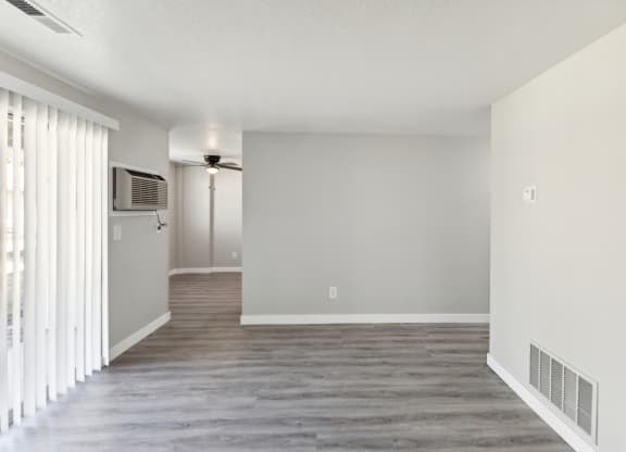 an empty living room with a window and a wall mounted tv