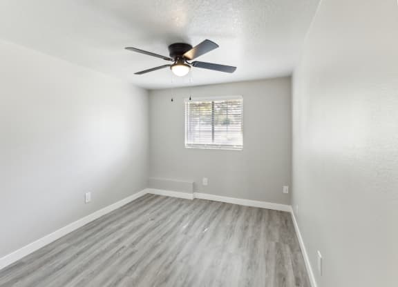 an empty living room with a ceiling fan and a window