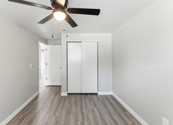 a renovated living room with white walls and a ceiling fan