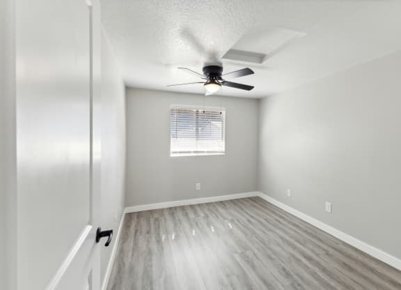 an empty bedroom with a ceiling fan and a window