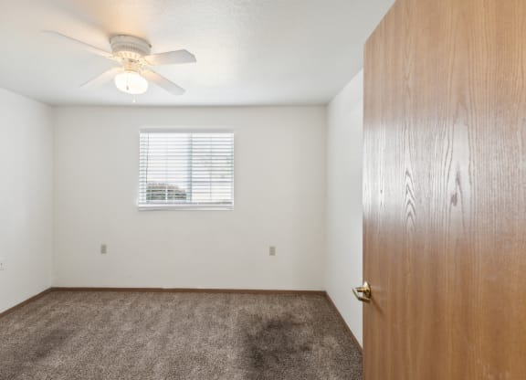 an empty bedroom with a closet and a ceiling fan