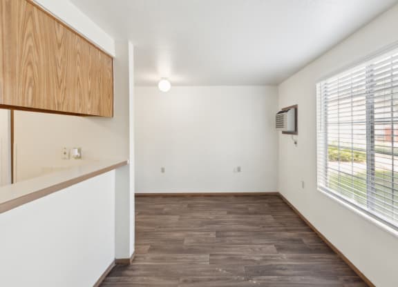an empty living room with a large window and a kitchen