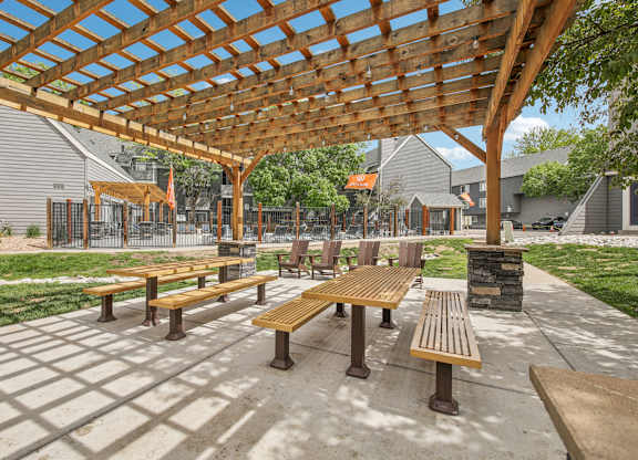 A wooden pergola with benches is in the foreground of the image.