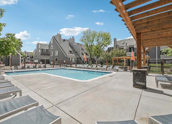 A large outdoor swimming pool surrounded by lounge chairs and umbrellas.