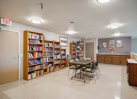 a library with a table and chairs and a book shelf filled with books