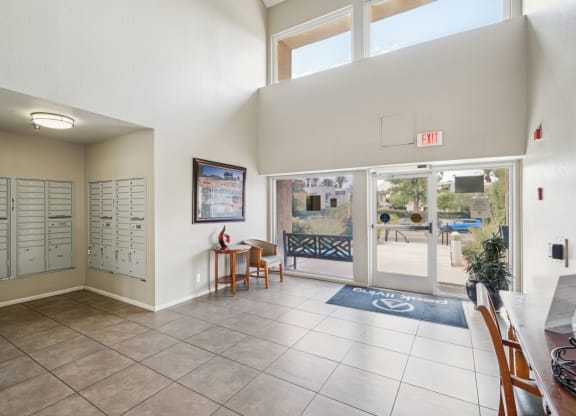 the entrance to a clubhouse with doors to the pool and a table with chairs