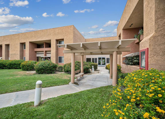 a view of the entrance to a building with grass and flowers