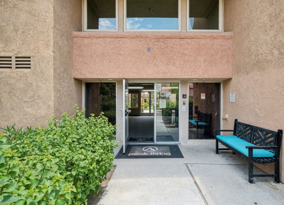 an entrance to a building with doors and a bench
